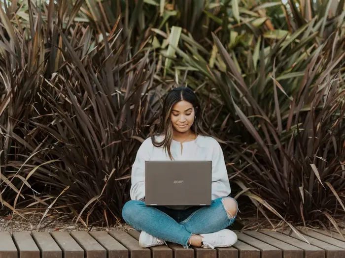 Young woman sitting outdoors with a laptop on wooden decking, showing easy access to Local Service Index services